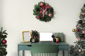 Workplace with blank laptop and Christmas trees in office