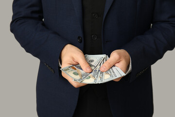 Young businessman with bribe on light background, closeup