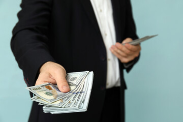 Young businessman with bribe on blue background, closeup