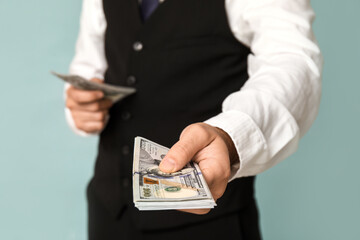 Young businessman with bribe on blue background, closeup