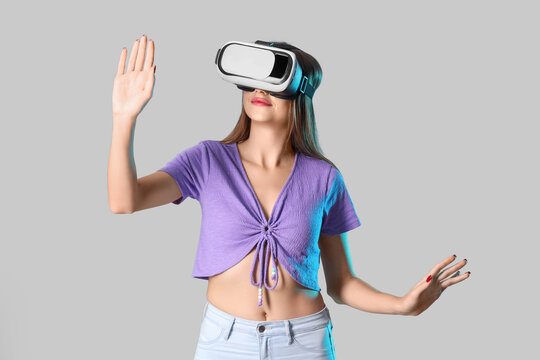 Young woman using VR glasses on light background