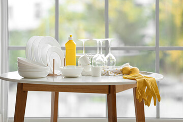Set of white dishes with cleaning supplies and lemons on table in kitchen - obrazy, fototapety, plakaty