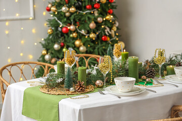 Festive dining table with Christmas setting and fir branches in room