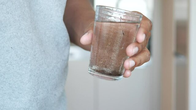 holding dirty glass of water 