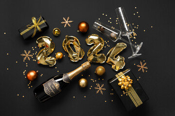 Composition with figure 2024 made of balloons, Christmas gifts, champagne and decorations on dark background
