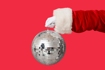 Santa hand with disco ball on red background, closeup