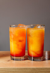A highball glass of Tequila Sunrise cocktails on a wooden bar counter