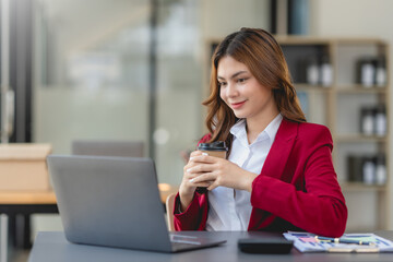 Successful businesswoman working and holding coffee cup at office. Confident businesswoman sitting happily in the office.