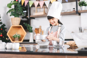 Little asian girl making cake and cooking food for Christmas cake and dinner party on holidays - obrazy, fototapety, plakaty