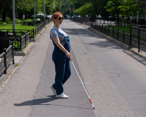 Blind pregnant woman crosses the street with the help of a tactile cane.