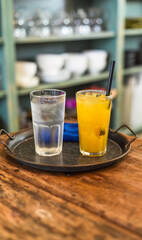 Glass of passion fruit juice with glass of water with ice on a tray in the kitchen