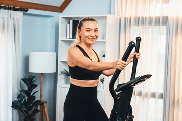 Active senior woman running on elliptical running machine at home portrait as fitness healthy...