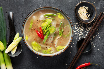 Bowl of leek soup with chili pepper on dark background. Food concept