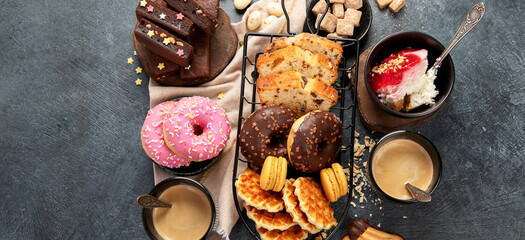 White coffee with delicious cookie, donuts, cake, sugar, waffles. Hot drink with sweets on dark...