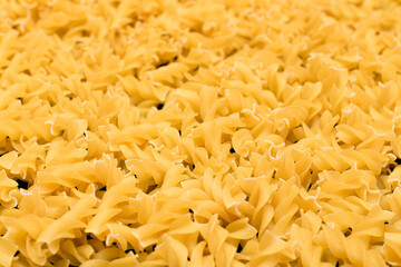 Uncooed Fusilli Pasta - Background. Texture of Bright Golden Dry Macaroni