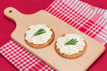 Crispy Cracker Sandwich with Cream Cheese and Rosemary on Wooden Cooking Board on Magenta Background