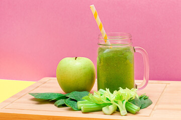Fresh Green Smoothie of Apple, Celery, and Spinach in Glass Smoothie Jar with Yellow Cocktail Straw...