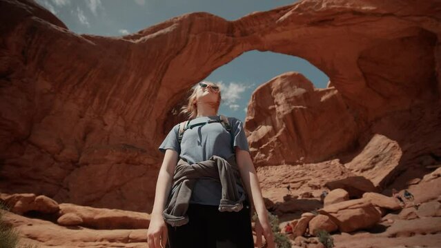 Female hiker looking around underneath beautiful natural canyon arches