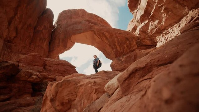 Female hiker looking around underneath beautiful natural canyon arches