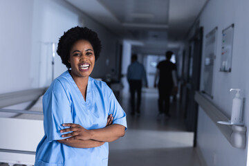 Portrait of happy african american female doctor in hospital corridor with copy space