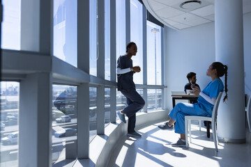 Diverse doctors talking in hospital corridor with copy space