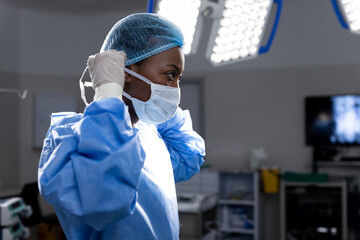 African american female doctor wearing face mask in hospital operating room