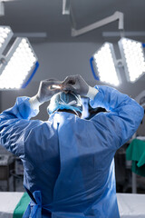 Back of african american female doctor wearing face mask in hospital operating room