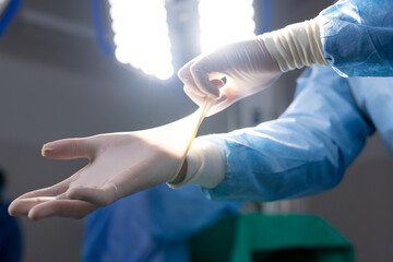 Hands of asian female doctor wearing protective gloves in hospital operating room