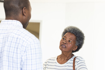 African american male doctor talking with senior woman in hospital reception