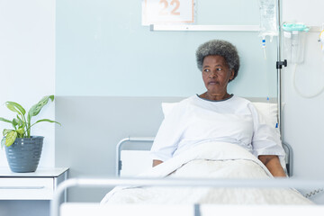 African american senior female patient lying in bed in sunny hospital room
