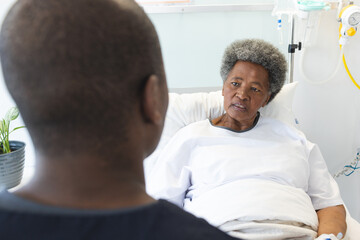 Fototapeta premium African american male doctor talking with senior female patient in hospital room