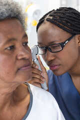 African american female doctor testing ear of senior female patient in hospital room