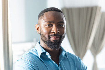 Portrait of happy african american male doctor in sunny hospital room