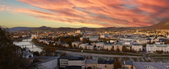 Fotobehang Autumn season at a historic city of Salzburg with Salzach river in beautiful golden evening light sky and colorful of autumn at sunset, Salzburger Land, Austria © SASITHORN