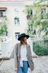 Beautiful brunette woman in hat walking in autumn city