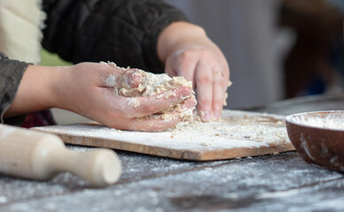 A woman kneads the dough with her hands