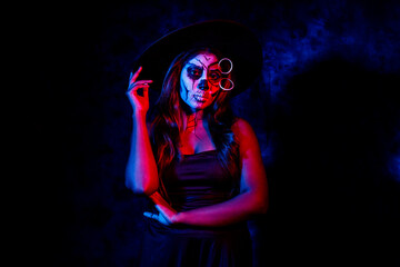 A women with Halloween Makeup in blue red light giving out a horror look wearing black gown in...