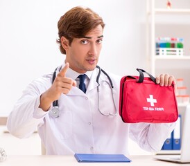Young doctor with first aid kit in hospital