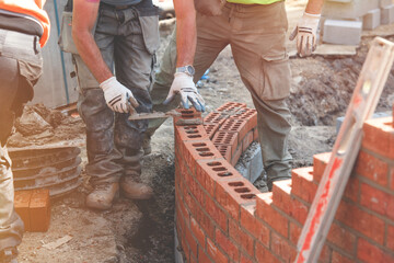 Industrial bricklayer laying bricks on cement mix  on a curved wall