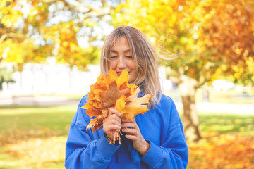 Asian woman in blue sweatshirt walking in Autumn park