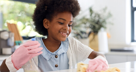 Child, gloves and happy in kitchen for cleaning, learning housekeeping as youth in home. Black girl, smile and cloth with sanitizer to shine counter and disinfectant surface in house with detergent