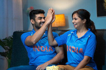 Excited happy couples Indian Team Jersey Celebrating win or victory while watching tv or television...