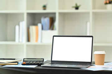 Financier workplace with laptop computer, calculator, paper cup and documents on black table