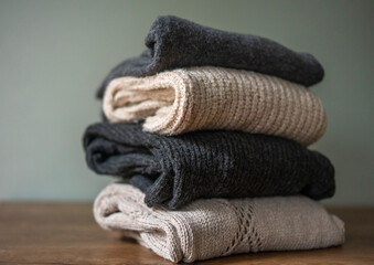 A stack of warm wool sweaters in neutral colors. Warm winter clothes