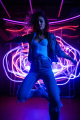 A beautiful young girl dances dynamically and passionately, illuminated by colorful neon lights. Let's go to a party!