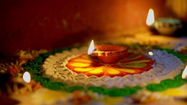 diwali diya or oil lamp lit on colorful rangoli. closeup shot of diwali diya 