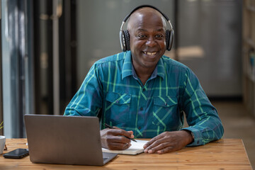 Senior black man wearing headphones enjoying listening to music or something interesting to relax...