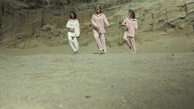 Three Caucasian women in casual clothes are dancing. dance rehearsal. three women in the desert. dynamic dance. Record high quality video in Full HD format.