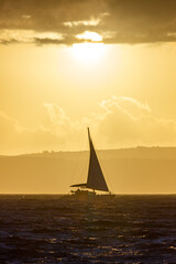 Fototapeta premium Boat sailing on the sea in sunset in front of Sun