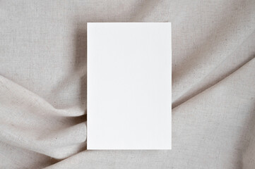 Blank white paper card mockup on neutral beige oat color crumpled linen fabric background with soft...